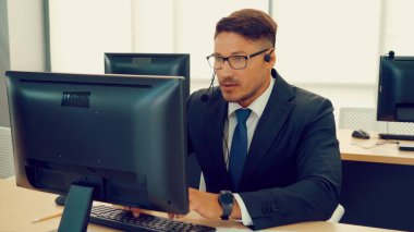 Ofiste çalışan kulaklık takan işadamları uzak müşteri ya da meslektaşlarını desteklemek için çalışıyorlar. Arama merkezi, tele pazarlama, müşteri destek acentesi telefon görüşmesinde hizmet sunar.