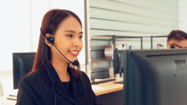 Ofiste çalışan kulaklık takan işadamları uzak müşteri ya da meslektaşlarını desteklemek için çalışıyorlar. Arama merkezi, tele pazarlama, müşteri destek acentesi telefon görüşmesinde hizmet sunar.