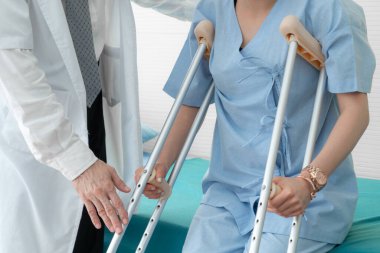 Doktor hastanede koltuk değnekli hastayla ilgileniyor. Fizyoterapist ve bacak yaralanması konsepti.