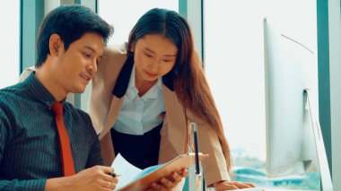 İki iş adamı toplantı odasında proje stratejisi hakkında konuşuyor. İş adamı, mali veri raporu hakkında sohbet ve tavsiyelerde bulunurken, modern işyerindeki iş arkadaşıyla proje planlamasını tartıştı.