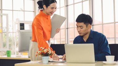 İki iş adamı toplantı odasında proje stratejisi hakkında konuşuyor. İş adamı, mali veri raporu hakkında sohbet ve tavsiyelerde bulunurken, modern işyerindeki iş arkadaşıyla proje planlamasını tartıştı.