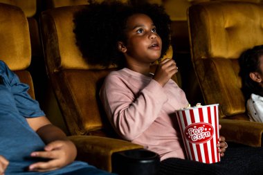 Üç çocuk eğleniyor ve sinemada film izlemekten zevk alıyor.