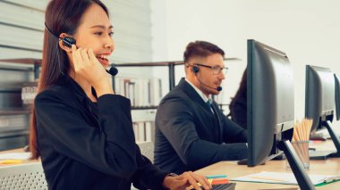 Ofiste çalışan kulaklık takan işadamları uzak müşteri ya da meslektaşlarını desteklemek için çalışıyorlar. Arama merkezi, tele pazarlama, müşteri destek acentesi telefon görüşmesinde hizmet sunar.