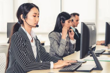 Ofiste çalışan kulaklık takan işadamları uzak müşteri ya da meslektaşlarını desteklemek için çalışıyorlar. Arama merkezi, tele pazarlama, müşteri destek acentesi telefon görüşmesinde hizmet sunar.