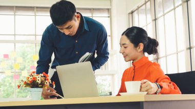 İki iş adamı toplantı odasında proje stratejisi hakkında konuşuyor. İş adamı, mali veri raporu hakkında sohbet ve tavsiyelerde bulunurken, modern işyerindeki iş arkadaşıyla proje planlamasını tartıştı.