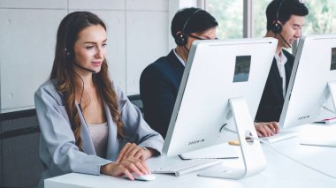 Ofiste çalışan kulaklık takan işadamları uzak müşteri ya da meslektaşlarını desteklemek için çalışıyorlar. Arama merkezi, tele pazarlama, müşteri destek acentesi telefon görüşmesinde hizmet sunar.