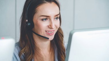 Ofiste çalışan kulaklık takan işadamları uzak müşteri ya da meslektaşlarını desteklemek için çalışıyorlar. Arama merkezi, tele pazarlama, müşteri destek acentesi telefon görüşmesinde hizmet sunar.