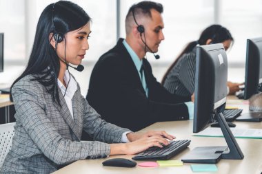 Ofiste çalışan kulaklık takan işadamları uzak müşteri ya da meslektaşlarını desteklemek için çalışıyorlar. Arama merkezi, tele pazarlama, müşteri destek acentesi telefon görüşmesinde hizmet sunar.