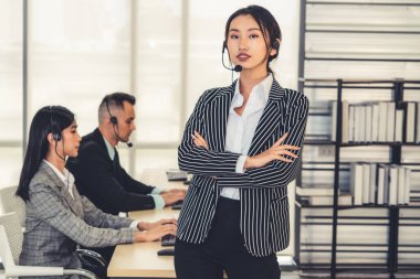Ofiste çalışan kulaklık takan işadamları uzak müşteri ya da meslektaşlarını desteklemek için çalışıyorlar. Arama merkezi, tele pazarlama, müşteri destek acentesi telefon görüşmesinde hizmet sunar.