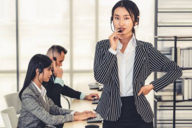 Ofiste çalışan kulaklık takan işadamları uzak müşteri ya da meslektaşlarını desteklemek için çalışıyorlar. Arama merkezi, tele pazarlama, müşteri destek acentesi telefon görüşmesinde hizmet sunar.
