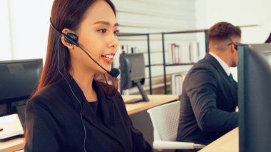 Ofiste çalışan kulaklık takan işadamları uzak müşteri ya da meslektaşlarını desteklemek için çalışıyorlar. Arama merkezi, tele pazarlama, müşteri destek acentesi telefon görüşmesinde hizmet sunar.