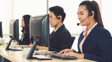 Ofiste çalışan kulaklık takan işadamları uzak müşteri ya da meslektaşlarını desteklemek için çalışıyorlar. Arama merkezi, tele pazarlama, müşteri destek acentesi telefon görüşmesinde hizmet sunar.