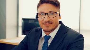 Ofiste çalışan kulaklık takan işadamları uzak müşteri ya da meslektaşlarını desteklemek için çalışıyorlar. Arama merkezi, tele pazarlama, müşteri destek acentesi telefon görüşmesinde hizmet sunar.