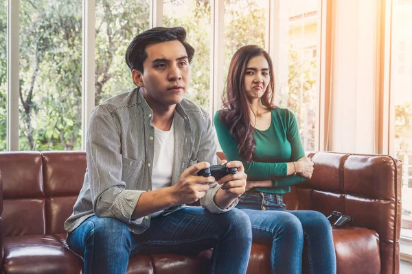 Young Asian couple suffers from computer games addiction. Family problem concept.