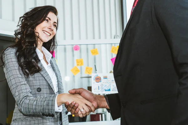 Business people handshake in corporate office showing professional agreement on a financial deal contract.