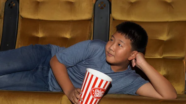 Menino Está Deitado Assistindo Filmes Comendo Pipocas Alegremente Desfrutando Cinema — Fotografia de Stock