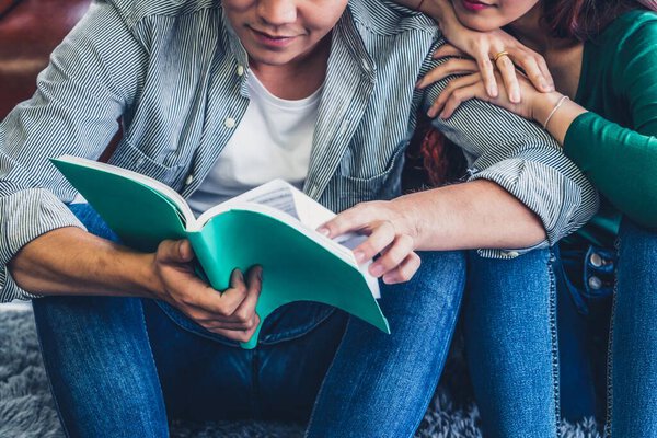 Young Asian couple reading book in living room. Love relationship and lifestyle concept.