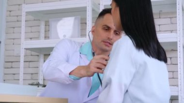 Profesyonel üniformalı doktor hastanedeki hastayı muayene ediyor.