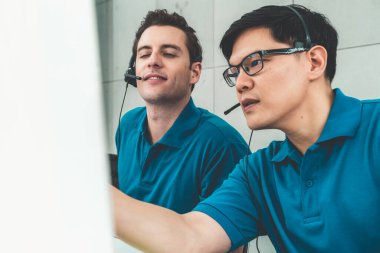 Ofiste çalışan kulaklık takan işadamları uzak müşteri ya da meslektaşlarını desteklemek için çalışıyorlar. Arama merkezi, tele pazarlama, müşteri destek acentesi telefon görüşmesinde hizmet sunar.