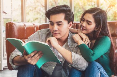Genç Asyalı çift oturma odasında kitap okuyor. Aşk ilişkisi ve yaşam tarzı kavramı.
