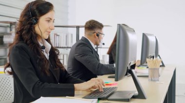 Ofiste çalışan kulaklık takan işadamları uzak müşteri ya da meslektaşlarını desteklemek için çalışıyorlar. Arama merkezi, tele pazarlama, müşteri destek acentesi telefon görüşmesinde hizmet sunar.