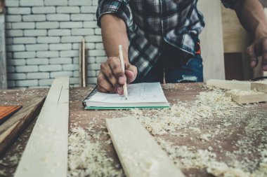 Marangoz atölyede ahşap işçiliği yapıyor. İnşaat malzemesi ya da ahşap mobilya üretiyor. Genç Asyalı marangoz zanaat için profesyonel araçlar kullanır. DIY üreticisi ve marangozluk konsepti.