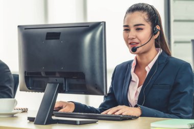 Ofiste çalışan kulaklık takan işadamları uzak müşteri ya da meslektaşlarını desteklemek için çalışıyorlar. Arama merkezi, tele pazarlama, müşteri destek acentesi telefon görüşmesinde hizmet sunar.