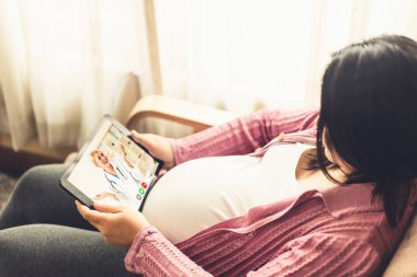 Hamile bir kadınla doğum öncesi bakım için internetten doktor teletıp hizmeti videosu. Canlı video çağrısı için internete bağlanan çevrimiçi mobil cihaz kullanarak evden uzak doktor sağlık danışmanı .