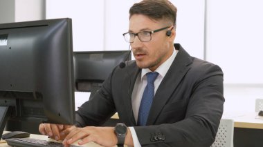 Ofiste çalışan kulaklık takan işadamları uzak müşteri ya da meslektaşlarını desteklemek için çalışıyorlar. Arama merkezi, tele pazarlama, müşteri destek acentesi telefon görüşmesinde hizmet sunar.