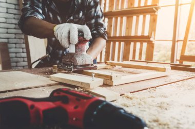 Marangoz atölyede ahşap işçiliği yapıyor. İnşaat malzemesi ya da ahşap mobilya üretiyor. Genç Asyalı marangoz zanaat için profesyonel araçlar kullanır. DIY üreticisi ve marangozluk konsepti.