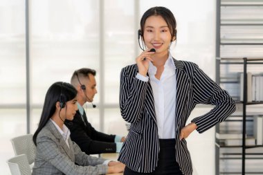 Ofiste çalışan kulaklık takan işadamları uzak müşteri ya da meslektaşlarını desteklemek için çalışıyorlar. Arama merkezi, tele pazarlama, müşteri destek acentesi telefon görüşmesinde hizmet sunar.