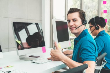 Ofiste çalışan kulaklık takan işadamları uzak müşteri ya da meslektaşlarını desteklemek için çalışıyorlar. Arama merkezi, tele pazarlama, müşteri destek acentesi telefon görüşmesinde hizmet sunar.