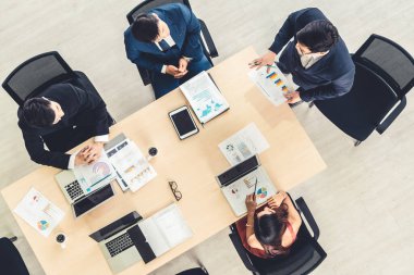 İş adamları grup toplantısı ofiste yukarıdan çekildi. İş kadınları, iş adamları ve ofis çalışanları, proje planlama belgeleriyle takım konferansında toplantı masasında çalışıyorlar. .