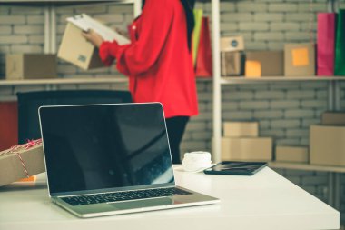 Nakliye kutusunun arka planında boş ekranı olan dizüstü bilgisayar. Çevrimiçi perakende satış mağazası, teslimat siparişi ve müşteri hizmetleri kavramı.