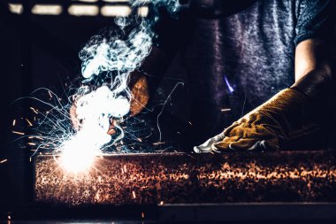 Fabrikada çelik kaynak makinesiyle çalışan metal kaynakçı güvenlik ekipmanı takıyor. El becerisi iş gücü kavramına göre metal imalatı ve inşaat bakım hizmeti.