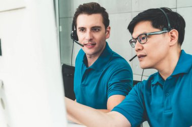 Ofiste çalışan kulaklık takan işadamları uzak müşteri ya da meslektaşlarını desteklemek için çalışıyorlar. Arama merkezi, tele pazarlama, müşteri destek acentesi telefon görüşmesinde hizmet sunar.