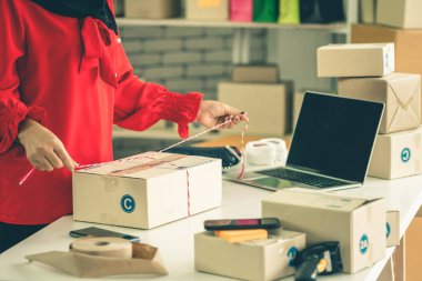 Çevrimiçi satıcı ev ofisinde çalışıyor ve teslimat kutusunu müşteriye paketliyor. İnternette e-ticaret yapan küçük işletme sahibi ya da girişimci.