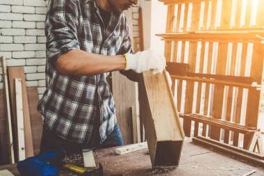Marangoz atölyede ahşap işçiliği yapıyor. İnşaat malzemesi ya da ahşap mobilya üretiyor. Genç Asyalı marangoz zanaat için profesyonel araçlar kullanır. DIY üreticisi ve marangozluk konsepti.