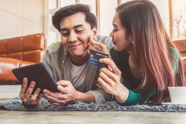 Young couple use credit card for online shopping on internet website at home. Number on the credit card is mock up. No personal information shown on the credit card. Online business shopping concept.