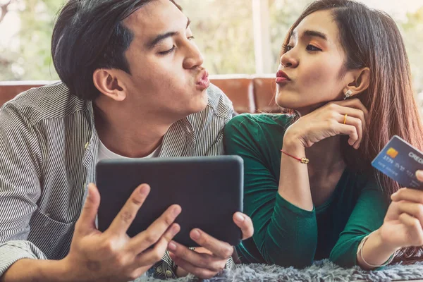 Young couple use credit card for online shopping on internet website at home. Number on the credit card is mock up. No personal information shown on the credit card. Online business shopping concept.