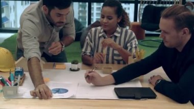 Yaratıcı iş adamları grubu iş yerindeki ofis masasında sohbet ediyorlar..