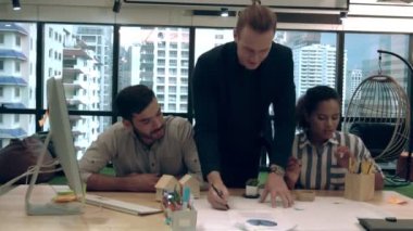 Yaratıcı iş adamları grubu iş yerindeki ofis masasında sohbet ediyorlar..