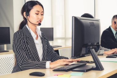 Ofiste çalışan kulaklık takan işadamları uzak müşteri ya da meslektaşlarını desteklemek için çalışıyorlar. Arama merkezi, tele pazarlama, müşteri destek acentesi telefon görüşmesinde hizmet sunar.