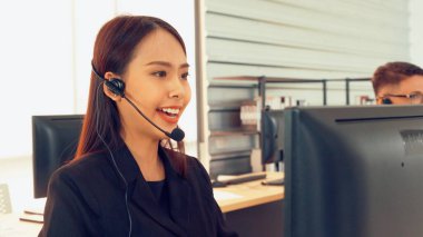 Ofiste çalışan kulaklık takan işadamları uzak müşteri ya da meslektaşlarını desteklemek için çalışıyorlar. Arama merkezi, tele pazarlama, müşteri destek acentesi telefon görüşmesinde hizmet sunar.