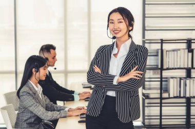 Ofiste çalışan kulaklık takan işadamları uzak müşteri ya da meslektaşlarını desteklemek için çalışıyorlar. Arama merkezi, tele pazarlama, müşteri destek acentesi telefon görüşmesinde hizmet sunar.