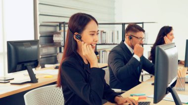 Ofiste çalışan kulaklık takan işadamları uzak müşteri ya da meslektaşlarını desteklemek için çalışıyorlar. Arama merkezi, tele pazarlama, müşteri destek acentesi telefon görüşmesinde hizmet sunar.