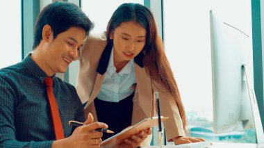 İki iş adamı toplantı odasında proje stratejisi hakkında konuşuyor. İş adamı, mali veri raporu hakkında sohbet ve tavsiyelerde bulunurken, modern işyerindeki iş arkadaşıyla proje planlamasını tartıştı.