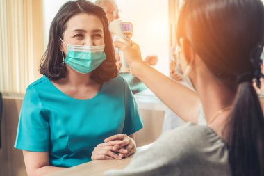 Ofiste ya da hastanede konuşurken resepsiyonist ve misafir maske takıyor. Covid 19 ve Coronavirus enfeksiyon koruması ve koruma politikası kavramı .