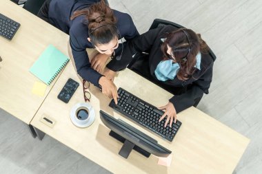 Ofiste üst kademeden kulaklık takan işadamları uzak müşteri ya da meslektaşlarını desteklemek için bilgisayarla çalışıyorlar. Çağrı merkezi, tele pazarlama acente servisi telefon ya da video konferans çağrısı.