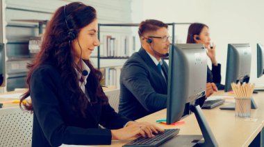 Ofiste çalışan kulaklık takan işadamları uzak müşteri ya da meslektaşlarını desteklemek için çalışıyorlar. Arama merkezi, tele pazarlama, müşteri destek acentesi telefon görüşmesinde hizmet sunar.